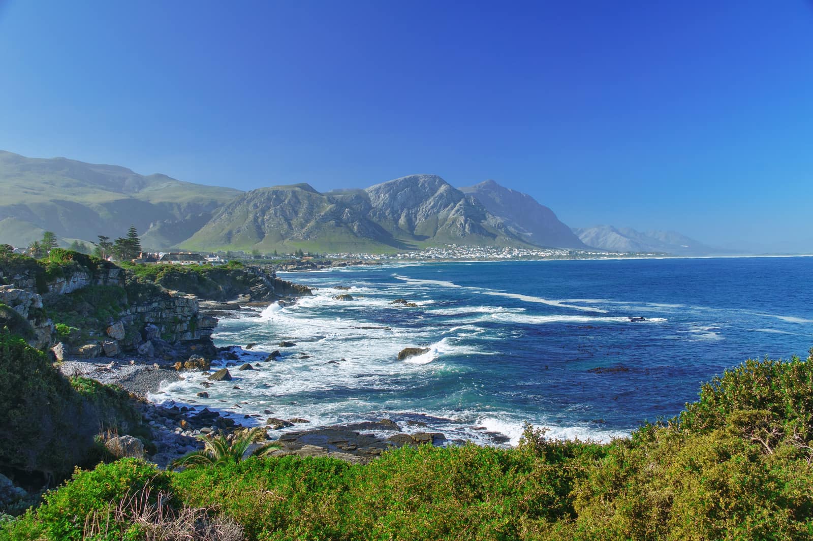 Felsküste von Hermanus mit Brandung und Bergen