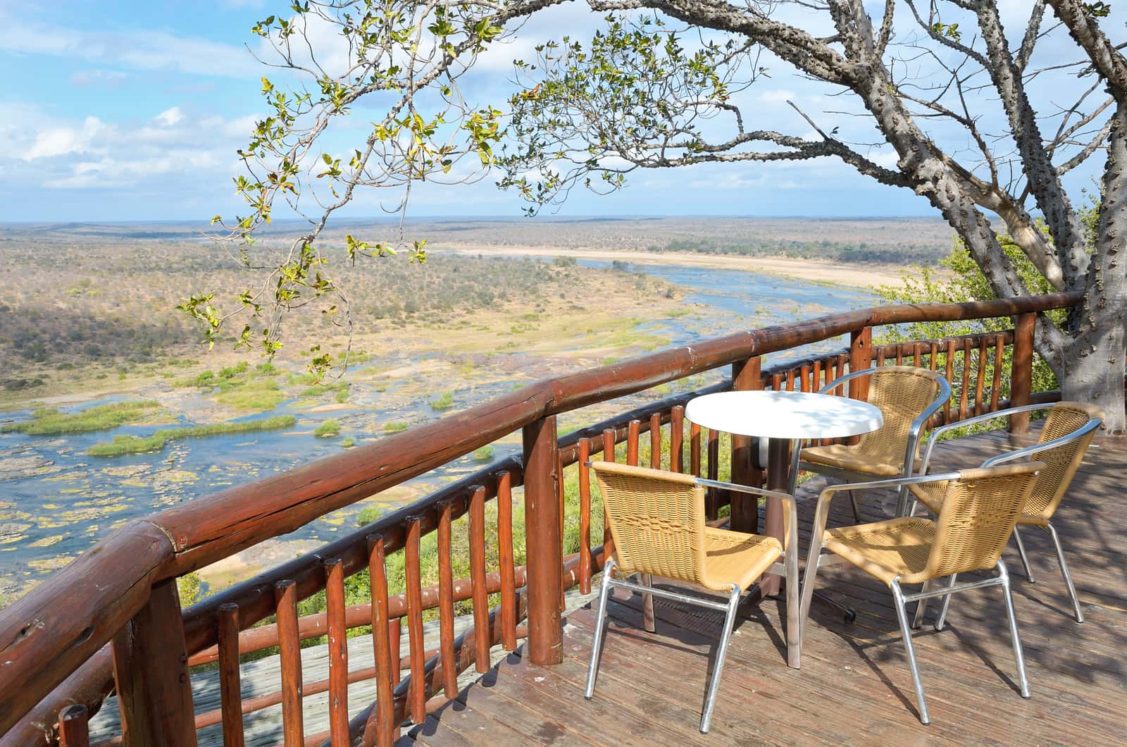Terrasse mit Tisch und Stühlen über einem Flusstal im Krüger-Nationalpark
